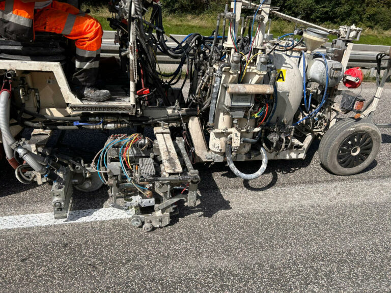 Straßenmarkierungsmaschine beim Auftragen frischer Markeierungsfarbe